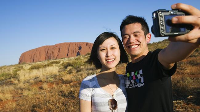 Tourists check out Australia’s most famous rock, which is traditionally owned by the Anangu people. Picture: NT Tourism