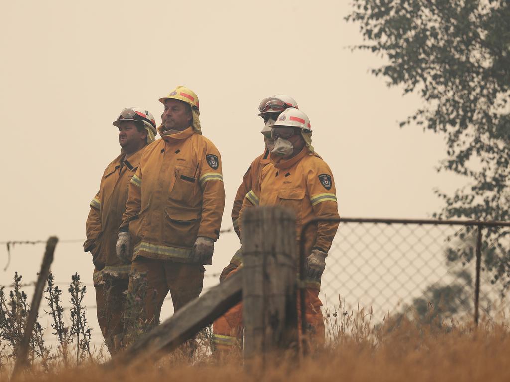 Tasmania Fire Service personnel watch on as a barn is engulfed in flames on the other side of a hill on Donnelley’s Road Geeveston. Picture: LUKE BOWDEN