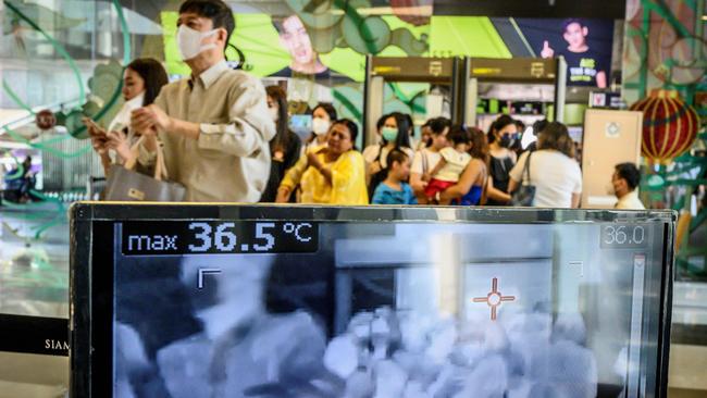 People with protective face masks pass in front of a thermal scanner as they enter a shopping mall in Bangkok on January 29, 2020. (Photo by Mladen ANTONOV / AFP)