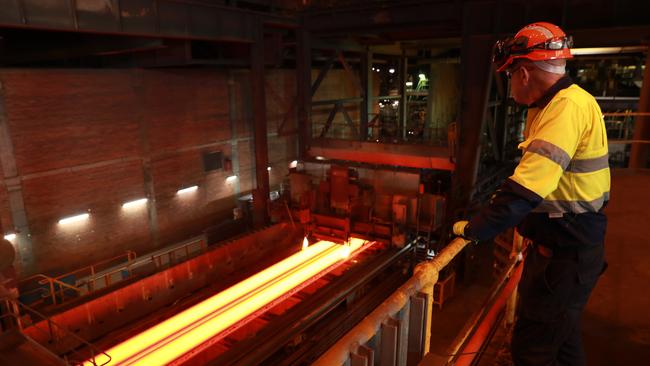 A worker watches as slabs of molten metal are cut to length at the Slabcaster at BlueScope Steel manufacturing plant in Port Kembla. Picture: John Feder