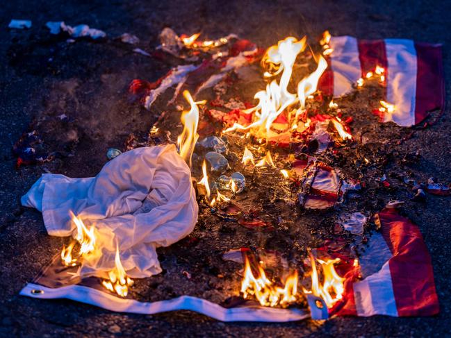 A burnt US flag is seen on the ground amid clashes with law enforcement in the streets surrounding the federal building during a protest following federal immigration operations in Los Angeles, California, on June 8, 2025. Demonstrators torched cars and scuffled with security forces in Los Angeles on June 8, as police kept protestors away from the National Guard troops President Donald Trump sent to the streets of the second biggest US city. (Photo by RINGO CHIU / AFP)