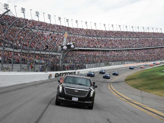 US President Donald Trump rides in the Presidential limousine during a pace lap ahead of the start of the Daytona 500 Nascar race at Daytona International Speedway in Daytona Beach, Florida, on February 16, 2025. (Photo by Chris Graythen / POOL / AFP)