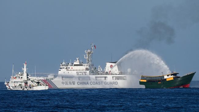 A Chinese coastguard ship fires a water cannon at a Philippine vessel in the disputed waters of the South China Sea. Picture: AFP