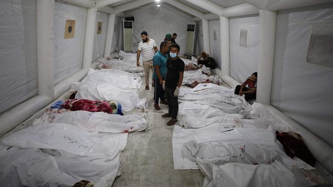 People stand over bodies of Palestinians killed in Israeli airstrikes on the Ahli Arab hospital in central Gaza. Picture: AFP