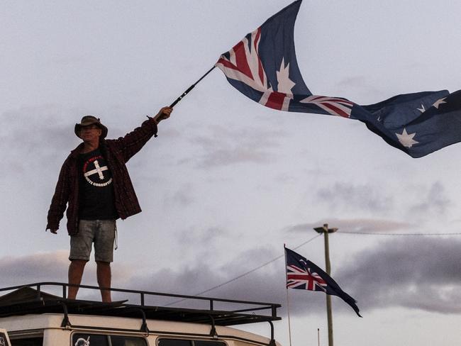 CANBERRA, AUSTRALIA - FEBRUARY 12: An anti-vaccine mandate protestor waves an upside down Australian flag as people gather at Exhibition Park on February 12, 2022 in Canberra, Australia. Anti-vaccine mandate protesters have been demonstrating in Canberra for a fortnight. Numbers have swelled today in what organisers billed as the biggest day of protests so far. The protestors have been ordered by Australian Federal Police to vacate the camp by midday on Sunday the 13th of February. (Photo by Brook Mitchell/Getty Images)