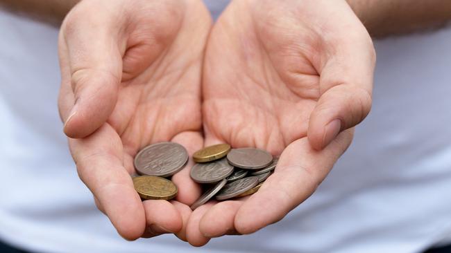 A caucasian man holds out some Australian coins; poor money generic hands