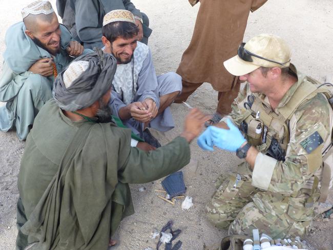 Corporal Tom Newkirk has a laugh with locals as he shows them his medical kit. Picture: Supplied