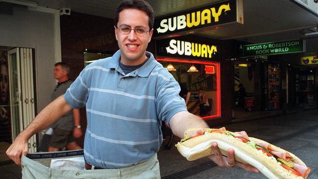 USA formerly overweight obese man Jared Fogle who lost 100 kg in weight after eating Subway sandwiches for one year. Here outside Subway outlet in Sydney holding his old size 61 inch trousers 14 May 2002.