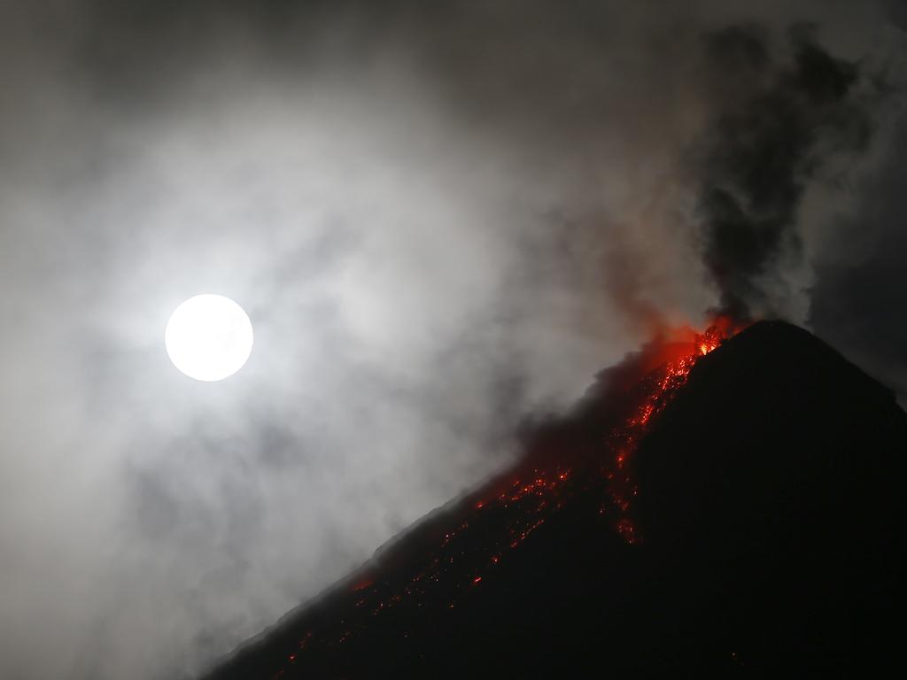 The super blue blood moon sets before dawn as lava cascades down the slopes of Mayon volcano during its sporadic mild eruption as seen from Sto. Domingo township, Albay province around 340 kilometers (200 miles) southeast of Manila, Philippines Thursday, Feb. 1, 2018. It’s the first time in 35 years a blue moon has synced up with a supermoon and a total lunar eclipse, or blood moon because of its red hue. Picture: AP