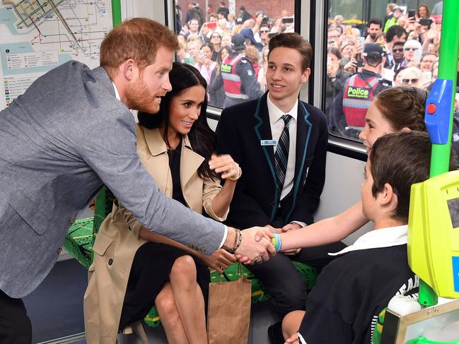 Britain's Prince Harry and his wife Meghan, Duchess of Sussex shake hands with local schoolchildren as they take a ride on a tram in Melbourne. Picture: AFP