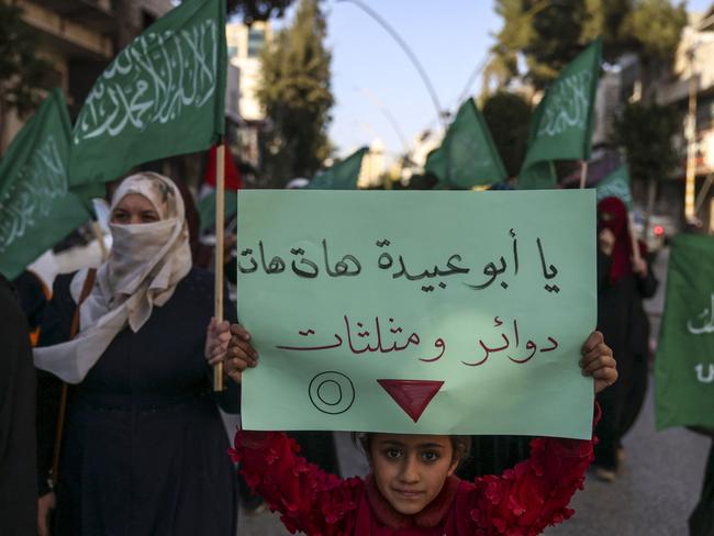 Palestinian protesters hold Islamic flags and a placard bearing the inverted "red triangle", a symbol that the Hamas movement's military wing Al-Qassam Brigades uses to identify Israeli targets in their videos, during a rally supporting the Gaza Strip. Picture: AFP