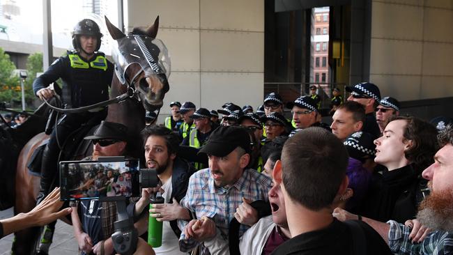 A police horse attempts to move the crowd outside the conference.