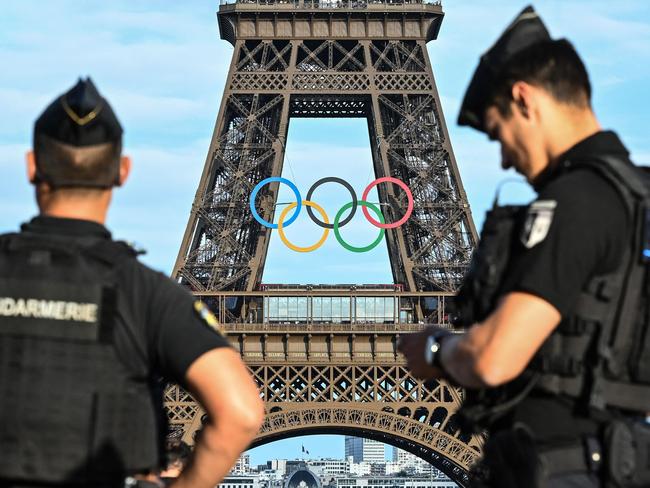 (FILES) French Gendarmerie officers patrol on in front of the Parvis des Droits de l'Homme across from the Eiffel Tower adorned with Olympic rings for the upcoming Paris 2024 Olympic Games, in Paris, on June 19, 2024. The 2024 Paris Olympic Games are set to begin with an unprecedented open-air ceremony on the river Seine on July 26, 2024, as most concerns so far relate to security arrangements for the opening festivities. (Photo by Stefano RELLANDINI / AFP)