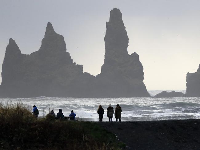 People walk on the black sanded beach in Vik, Iceland, near the Volcano Katla, Wednesday, Oct. 26, 2016. Katla Volcano has helped turn sleepy Vik, a community of 300 people some 110 miles (180 kilometers) east of the capital, Reykjavik, into a tourism hotspot. (AP Photo/Frank Augstein)