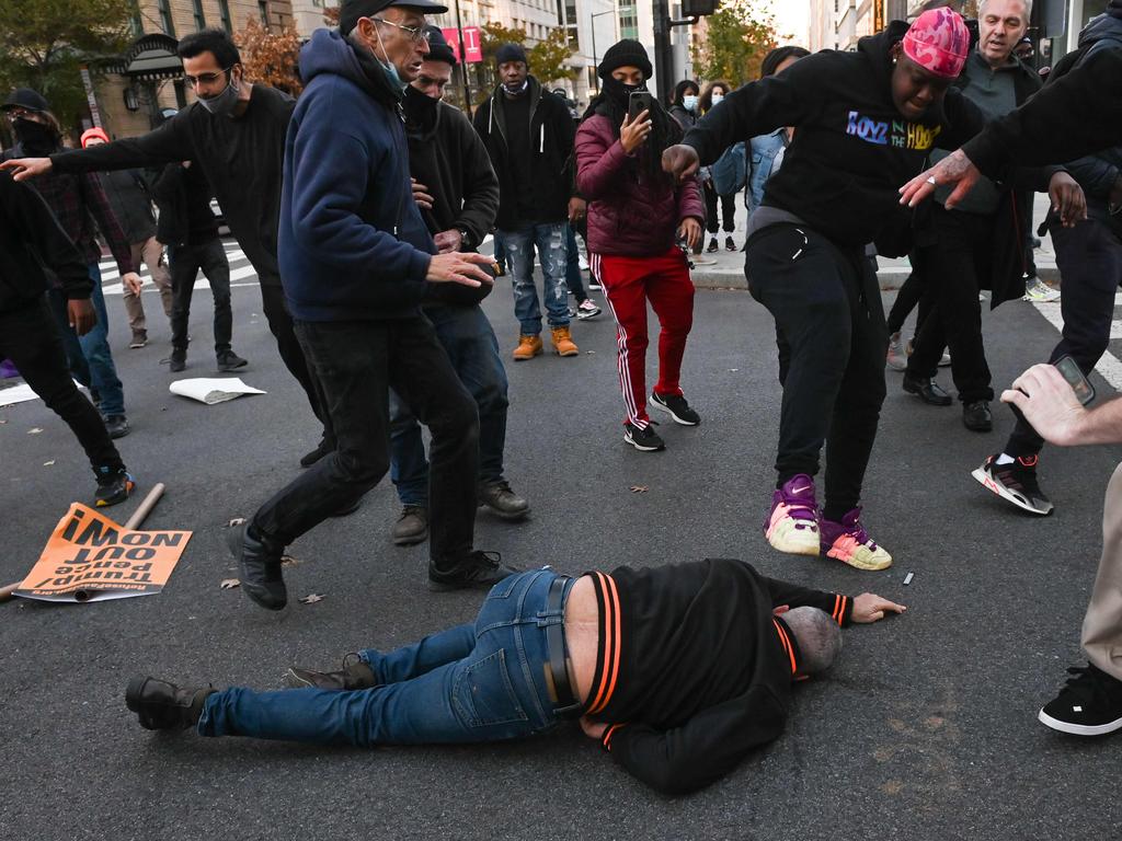 A supporter of US President Donald Trump lying on the ground is kicked as he is attacked by anti-Trump demonstrators in Black Lives Matter Plaza in Washington, DC. Picture: AFP