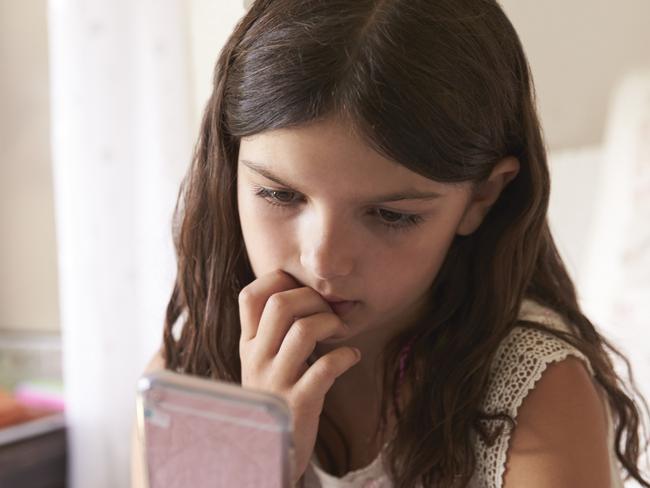 Young Girl In Bedroom Worried By Bullying Text Message