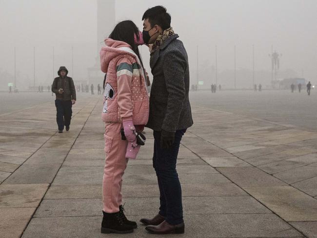 Taking no chances. A couple kisses through face masks in Tiananmen Square last week. Picture: Kevin Frayer/Getty Images