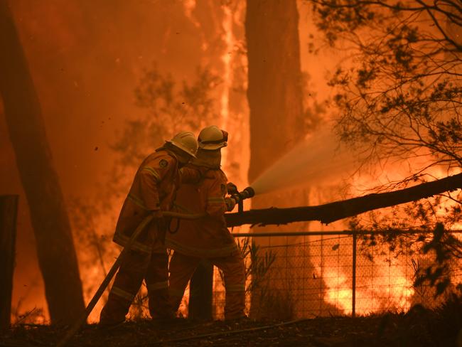 RFS volunteers and NSW Fire and Rescue officers protect a home on Wheelbarrow Ridge Rd being impacted by the Gospers Mountain fire near Colo Heights in November 2019. Picture: AAP