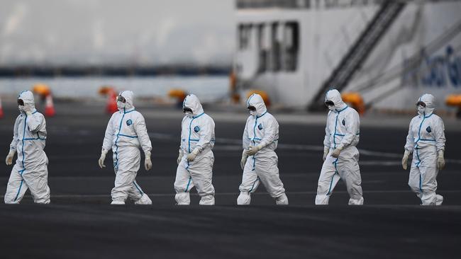 People wearing protective suits walk from the Diamond Princess cruise ship that is quarantined in Yokohama, Japan Picture: AFP