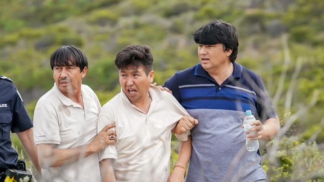 A heartbroken Charman Yari (middle) is led away be friends at Parsons Beach on Thursday.    Picture: AAP/MIKE BURTON