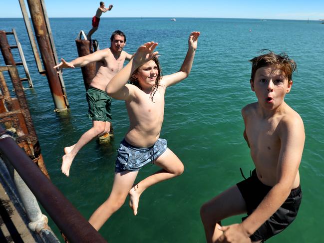 Shannon Breuer of Plympton, (0426197924), and his boys, Fox, 9,(Front), Dieter,12, and Griffin,14,(on back post) enjoying a bit of jetty jumping at Glenelg. 3 February 2024. Picture Dean Martin