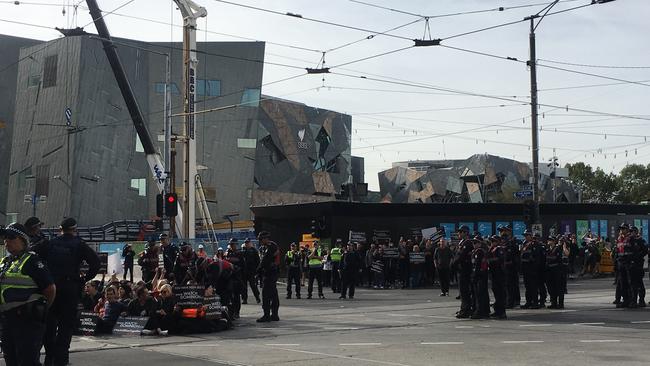 Police carry away individual protesters who have clustered themselves in the middle of the Melbourne CBD intersection. Picture: Remy Varga