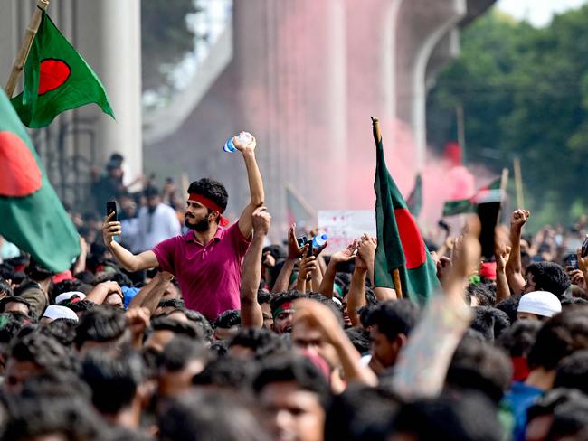 TOPSHOT - Anti-government protestors wave Bangladesh's national flag as they celebrate at Shahbag area, near Dhaka university in Dhaka on August 5, 2024. Protests in Bangladesh that began as student-led demonstrations against government hiring rules in July culminated on August 5, in the prime minister fleeing and the military announcing it would form an interim government. (Photo by Munir UZ ZAMAN / AFP)