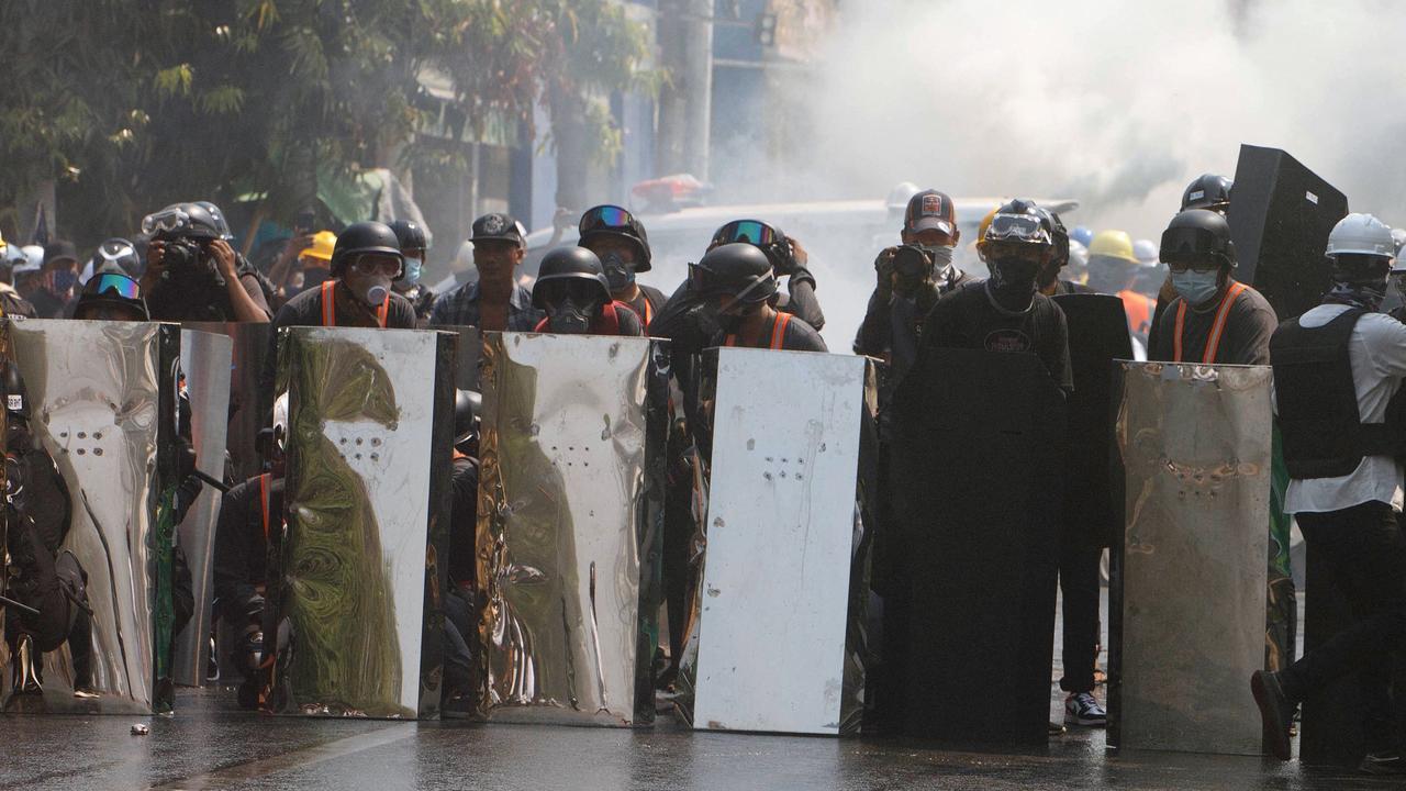 Protesters shelter behind shields as they face police Picture: STR/AFP