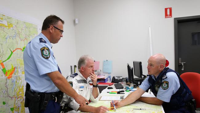 Inspector Scott McAlpine (standing) reviews a map with Senior Constable Steve Day and Senior Constable Erick Denis. Picture: Matthew Sullivan