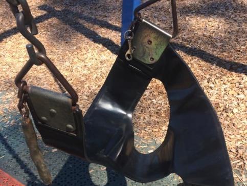 A broken swing on a children’s playground.