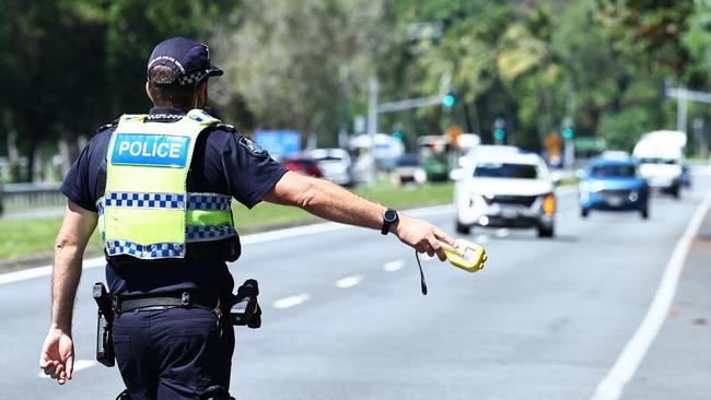 A Queensland Police traffic officer waves drivers to pull over to perform a random breath test on the Captain Cook Highway at Aeroglen. Picture: Brendan Radke