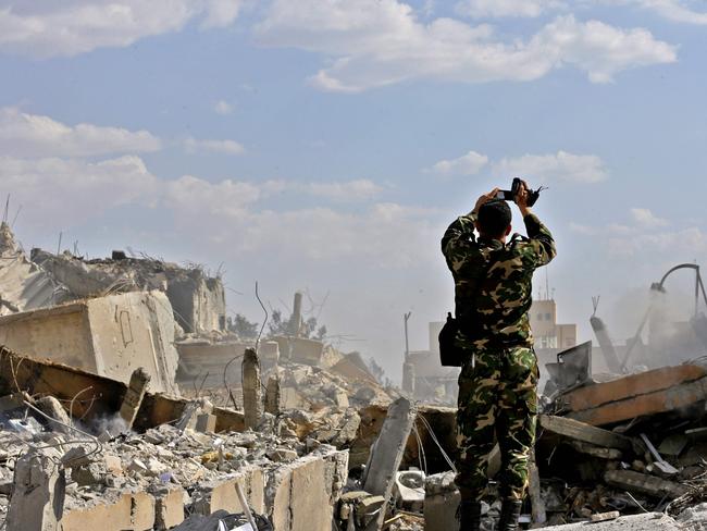 TOPSHOT - A Syrian soldier inspects the wreckage of a building described as part of the Scientific Studies and Research Centre (SSRC) compound in the Barzeh district, north of Damascus, during a press tour organised by the Syrian information ministry, on April 14, 2018. The United States, Britain and France launched strikes against Syrian President Bashar al-Assad's regime early on April 14 in response to an alleged chemical weapons attack after mulling military action for nearly a week. Syrian state news agency SANA reported several missiles hit a research centre in Barzeh, north of Damascus, 