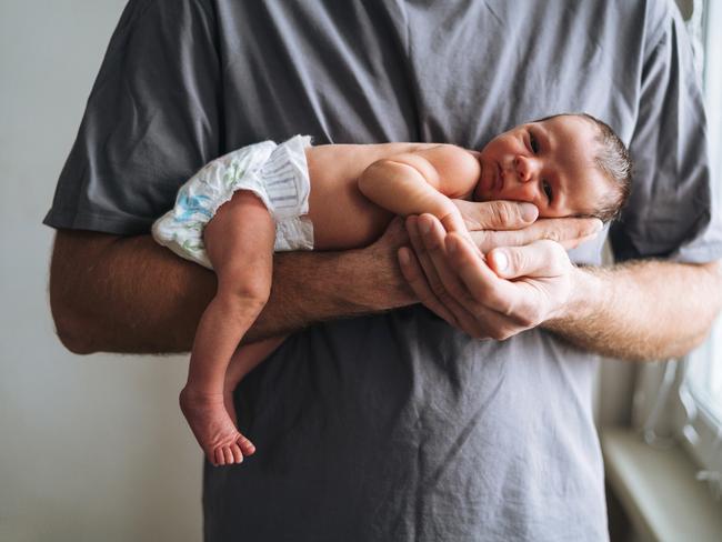 Young father with 2 weeks newborn baby boy in his hands near window at home. Picture: Getty Images