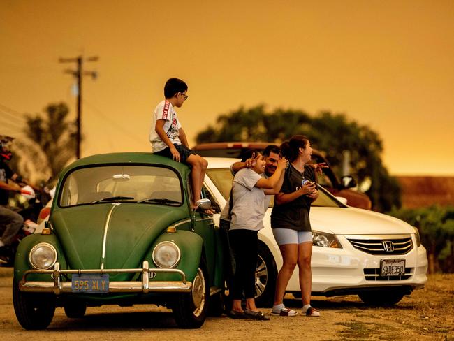 People pulled over near a vineyard watch a smoke plume from the larger LNU Lightning Complex fire, as flames continue to spread in Healdsburg, California. AFP