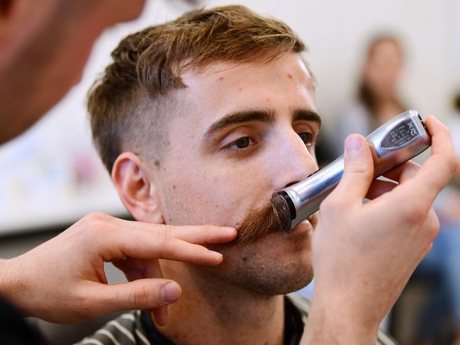 Crows Jordan Gallucci has his moustache shaved off by barber Grant Freeman at The Fellow Barber at Henley Beach. Picture: AAP/Mark Brake.