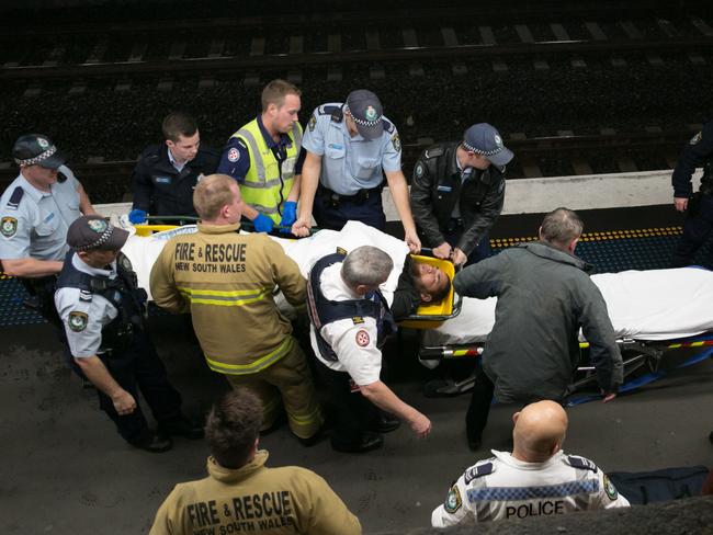 Emergency workers stretcher the man to a waiting ambulance. Picture: Damian Hofman