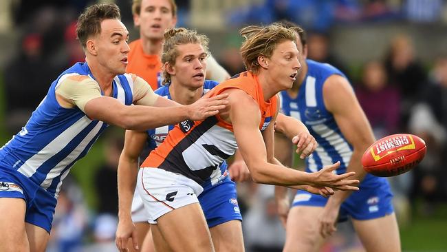 Lachie Whitfield gets a handball away under pressure.