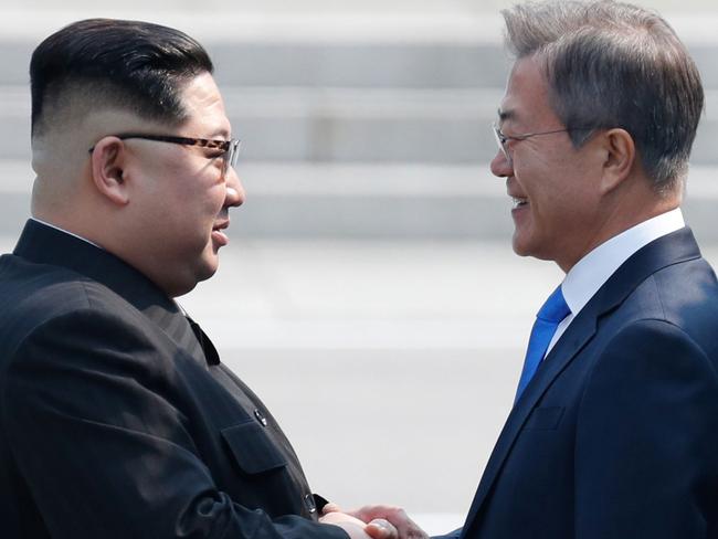 North Korea's leader Kim Jong Un (L) and South Korea's President Moon Jae-in shake hands at the Military Demarcation Line that divides their countries at Panmunjom on April 27, 2018. The two men briefly stepped back over the line into the North before walking to the Peace House building on the southern side of the truce village of Panmunjom for the summit -- only the third of its kind since hostilities ceased in 1953. / AFP PHOTO / Korea Summit Press Pool / Korea Summit Press Pool