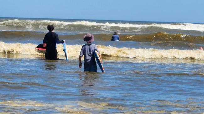 Kids swim in dirty-brown waves at Middleton Beach on Saturday, January 7, 2023.