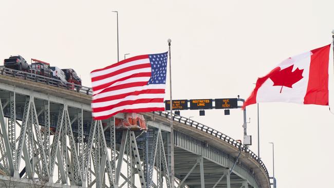 The US and Canadian flags fly on the US side of the St. Clair River near the Bluewater Bridge border crossing between Sarnia, Ontario and Port Huron, Michigan on January 29, 2025. (Photo by Geoff Robins / AFP)