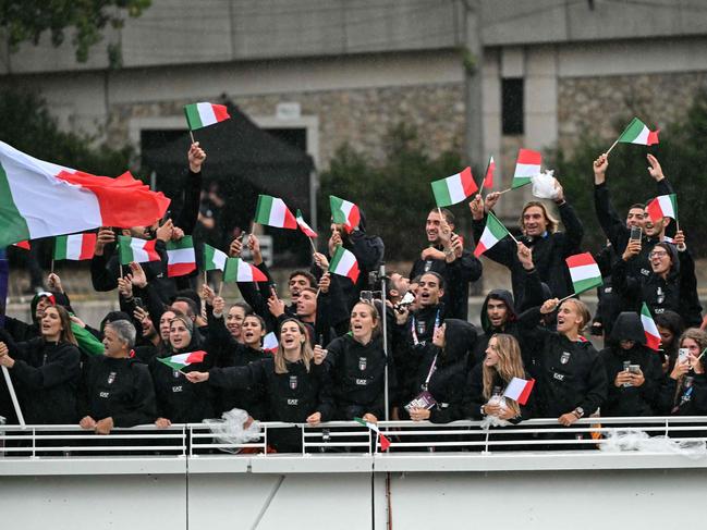 Athletes from Italy's delegation wave flags as they sail along the river Seine. Picture: AFP