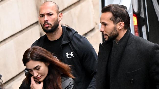 British-US former professional kickboxer and controversial influencer Andrew Tate (C) and his brother Tristan Tate (R) arrive handcuffed and escorted by police at a courthouse in Bucharest. Picture: AFP.