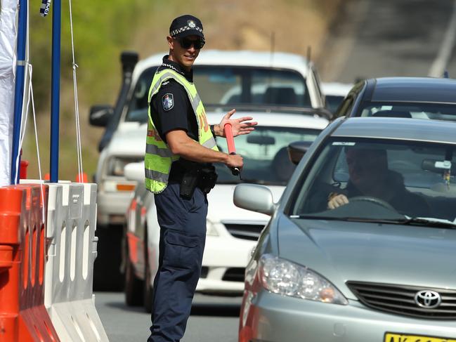 Queensland Police stop a NSW regsitered vehicle at the Miles Street / Ducat Street Street border checkpoint in Coolangatta Queensland for a secondary ID check as traffic backs up to Kennedy Drive in Tweed Heads NSW on Wednesday July 15. Photo Scott Powick Newscorp