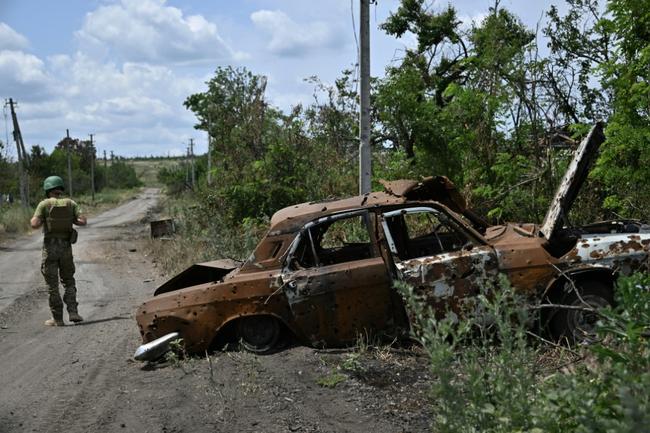 A Ukrainian serviceman walks past a destroyed car in the recaptured Donetsk village of Storozheve