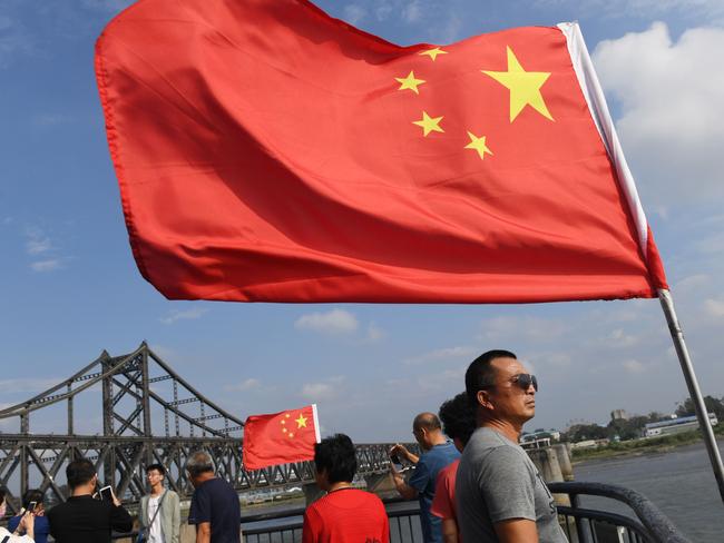 Chinese tourists stand near a Chinese flag. Picture: AFP