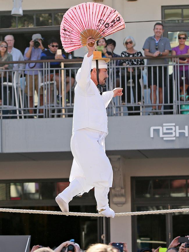 Master Kim walks the tight-rope above The Corso at Manly on Sydney's Northern Beaches. He was joined by a colourful display of Korean dancers & musicians who entertained a large crowed that gathered to see the spectacle. Picture: Troy Snook