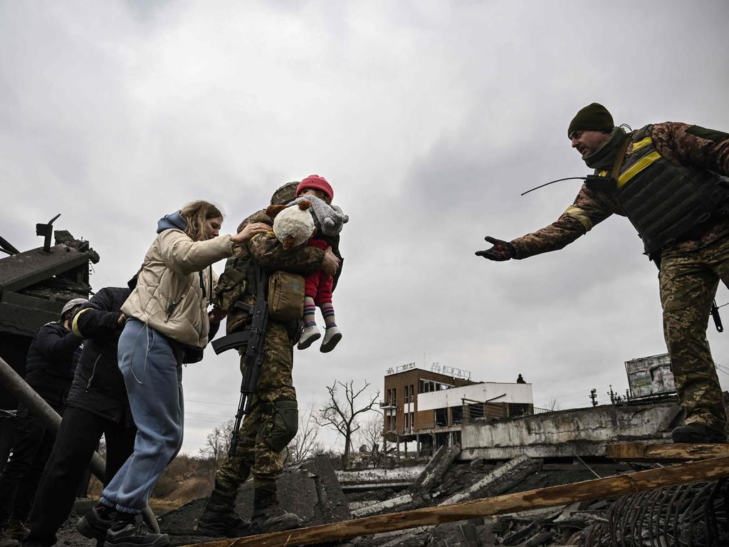 A Ukrainian serviceman carries a child while assisting people during heavy shelling and bombing in Ukraine. Picture: Aris Messinis / AFP.