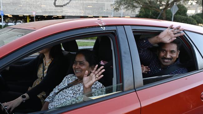 Priya and Nades Murugappan wave to waiting media after arriving at Brisbane airport. Picture: NCA NewsWire / Dan Peled