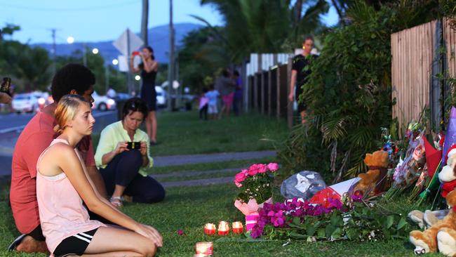 Aaron Oui and Jade Atkinson sit at a vigil of flowers and candles set up opposite the crime scene. Picture: Brendan Radke
