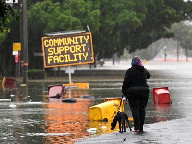 LISMORE, AUSTRALIA - MARCH 30: A woman walks her dog on a flooded road on March 30, 2022 in Lismore, Australia. Evacuation orders have been issued for towns across the NSW Northern Rivers region, with flash flooding expected as heavy rainfall continues. It is the second major flood event for the region this month. (Photo by Dan Peled/Getty Images)